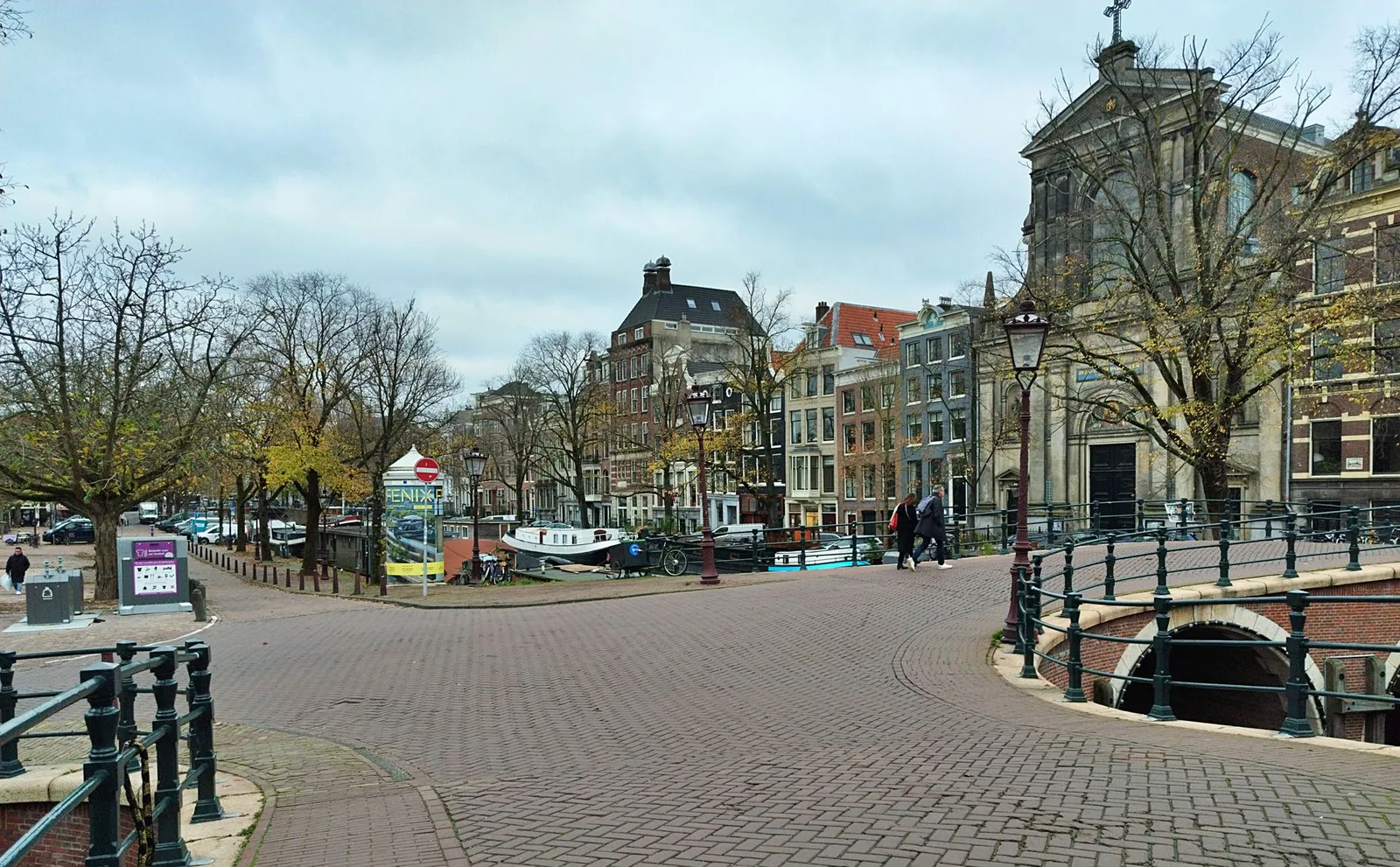 An empty cobblestone canal bridge in Amsterdam with classic Dutch architecture in autumn.