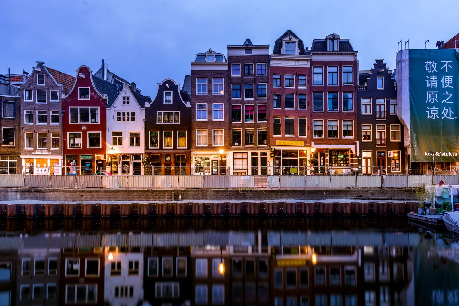 A picturesque view of colorful canal houses reflecting on the water in Amsterdam, Netherlands.