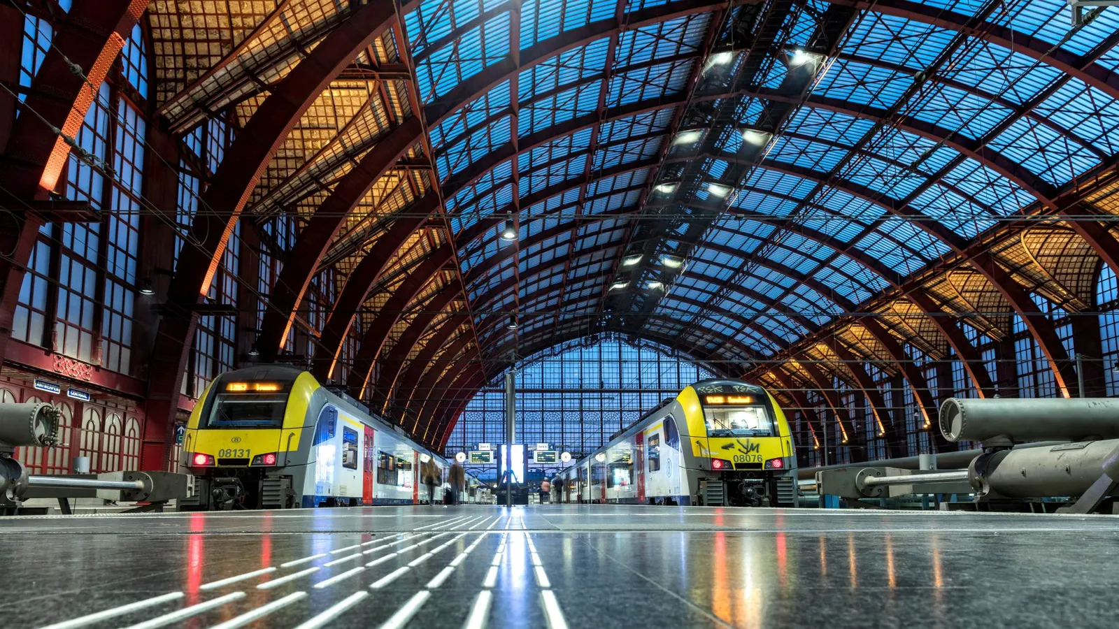 Interior view of Antwerp Central Station showcasing modern trains and stunning architecture.