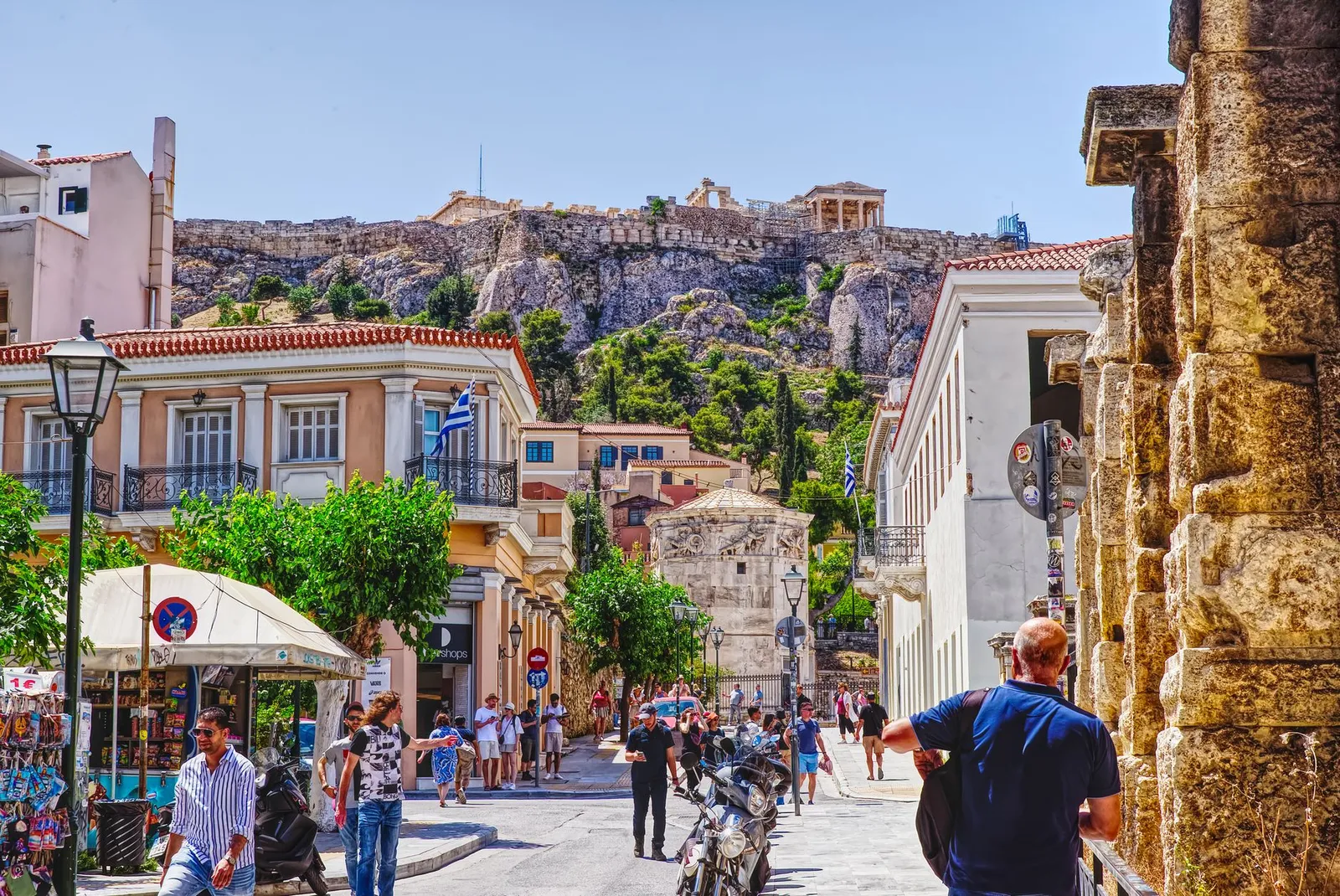 Bustling street in Athens with a view of the Acropolis, capturing local life and historic architecture.