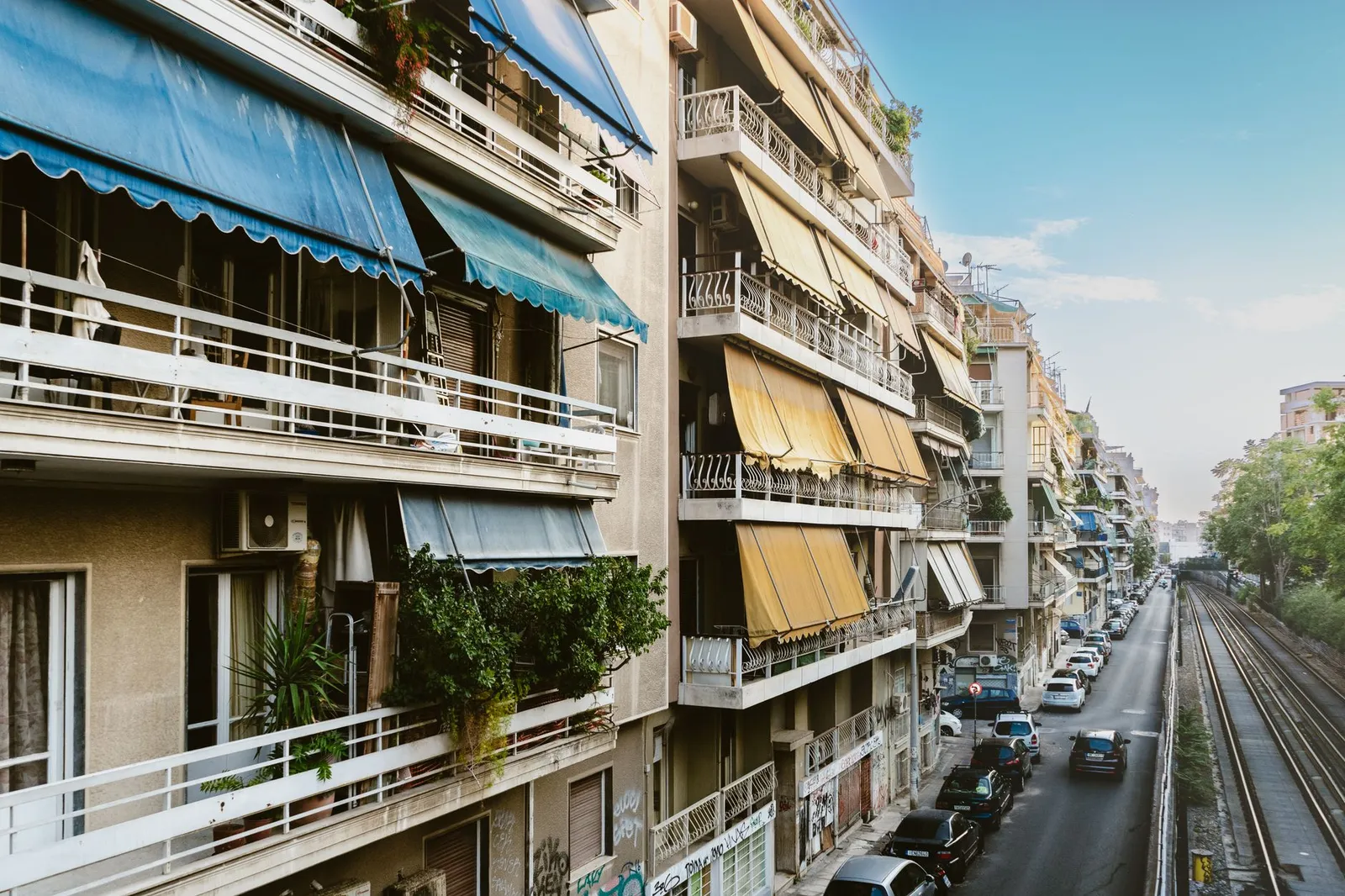 Charming view of residential buildings in Athens, Greece along a tranquil street and railway.