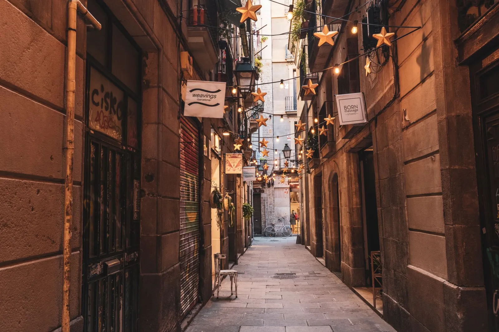 Captivating view of a narrow Barcelona alley adorned with star-shaped string lights and charming facades.