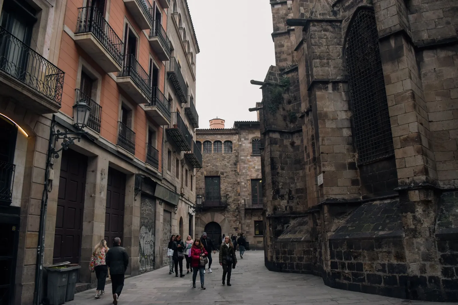 A bustling alley in Barcelona filled with people against historic buildings' backdrop.