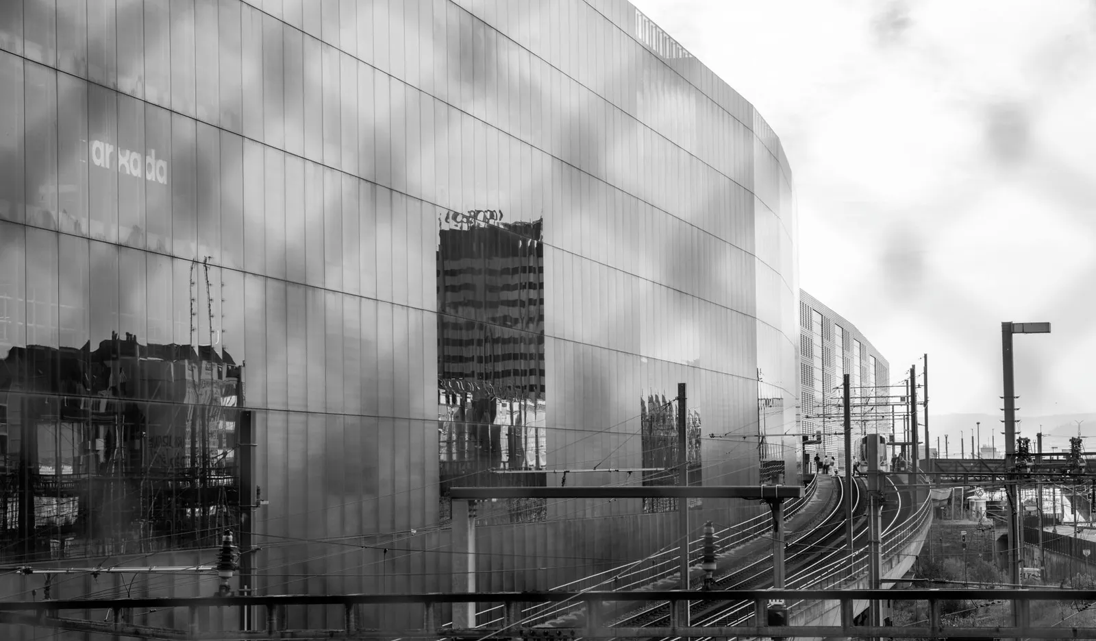 Black and white photo of modern facade reflection with tram tracks in Basel, Switzerland.
