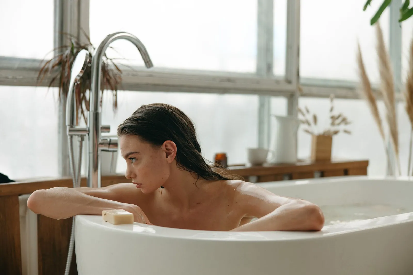 A woman indulging in a peaceful bath experience with natural light and relaxation.