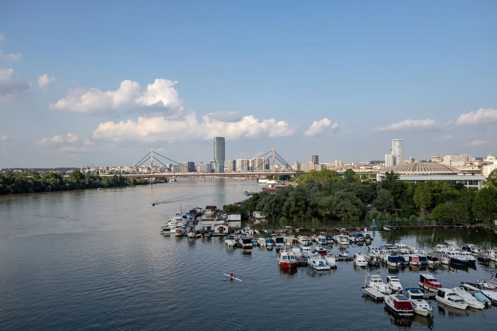 A serene scene of Belgrade's skyline and marina on the Sava River under a clear blue sky.