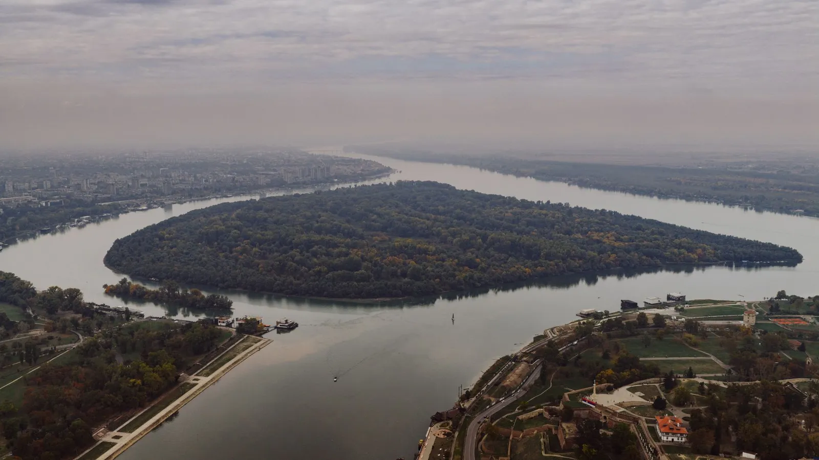 Stunning aerial shot of the river bend in Belgrade, Serbia, showcasing lush greenery and cityscape.