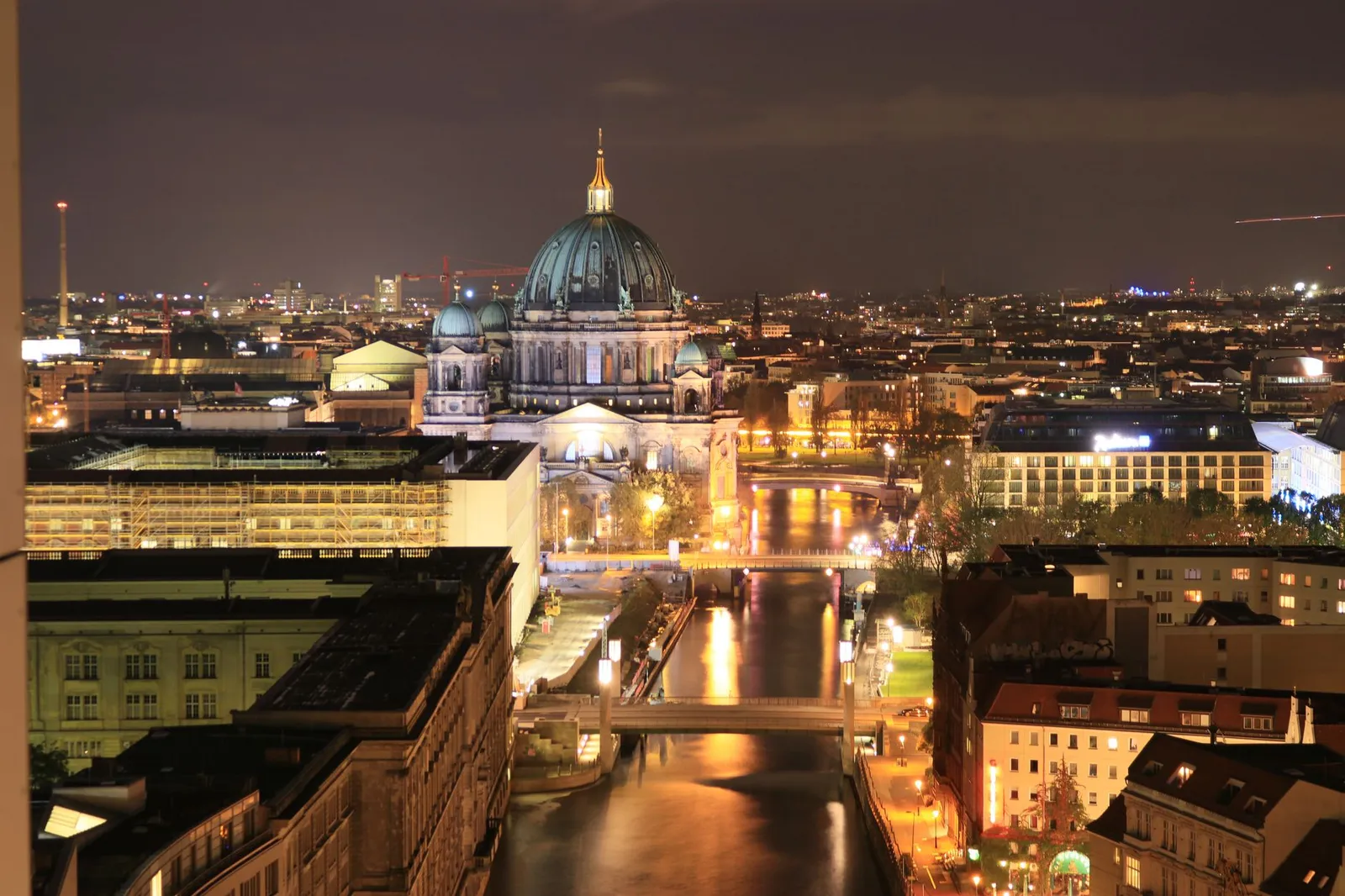 A breathtaking aerial shot of Berlin Cathedral illuminated at night, capturing the city's vibrant skyline and serene river.