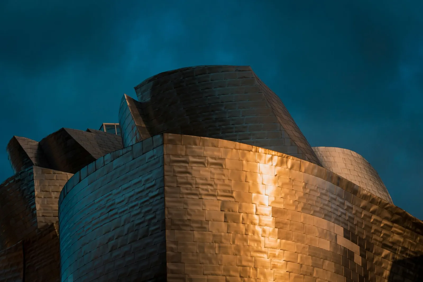 Close-up of the iconic Guggenheim Museum in Bilbao showing striking architecture against a moody sky.