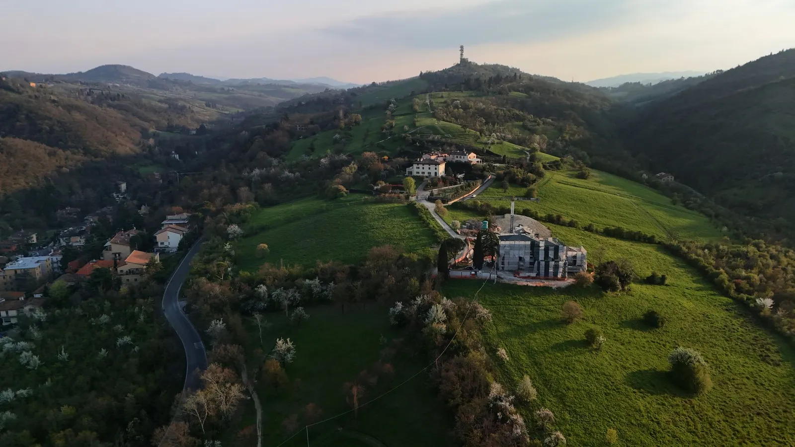 Breathtaking aerial image showcasing the lush green hills near Bologna, Italy, under a scenic sunset.