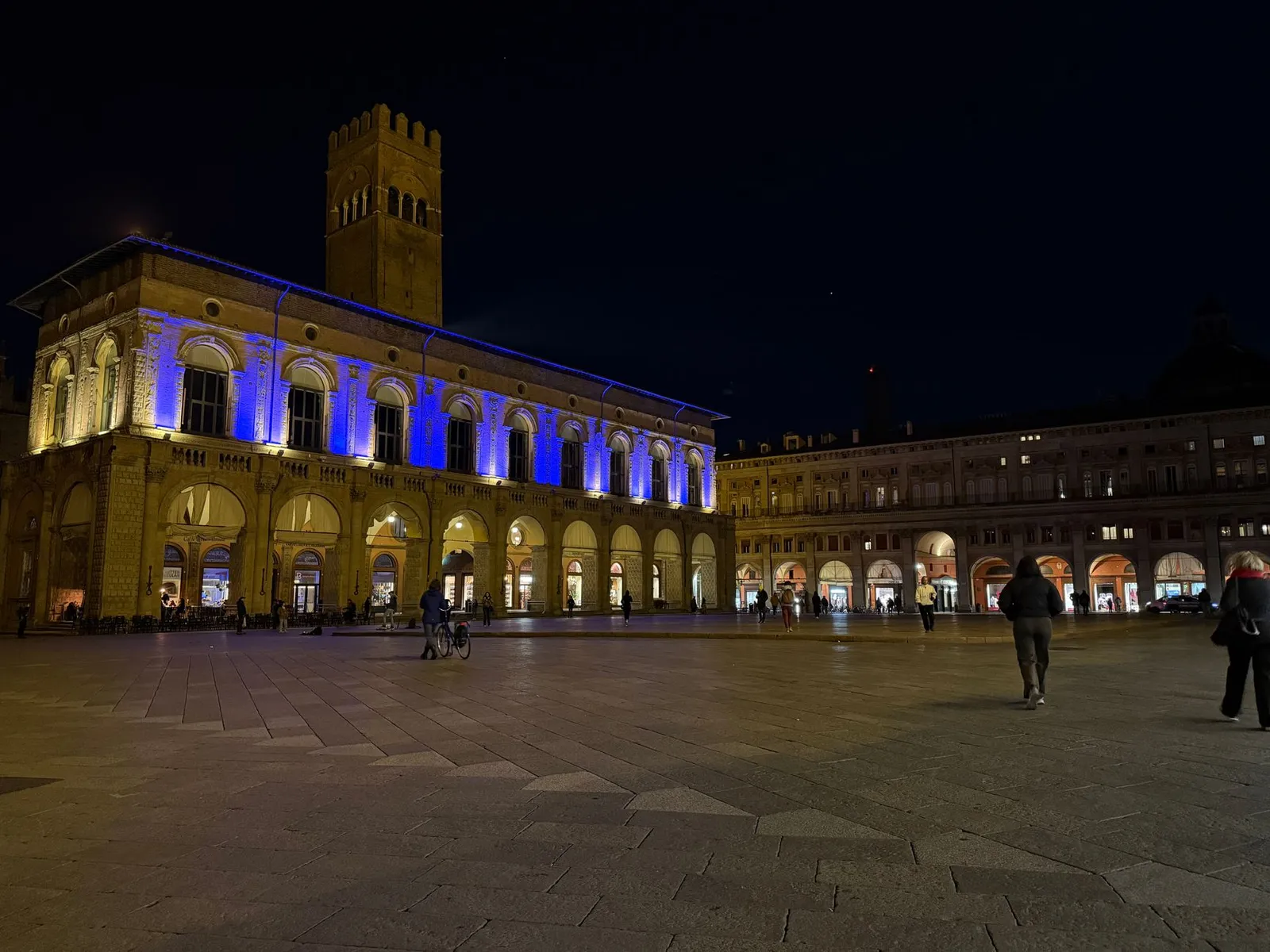 Stunning night view of Palazzo del Podestà, Bologna, illuminated with vibrant lights.