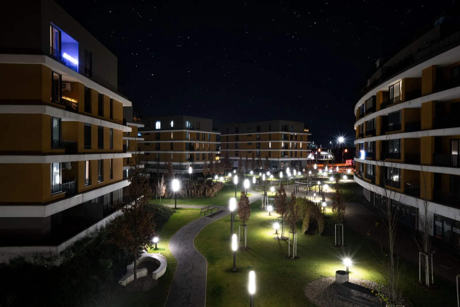 Illuminated modern apartment complex in Bratislava captured under a starry night sky.
