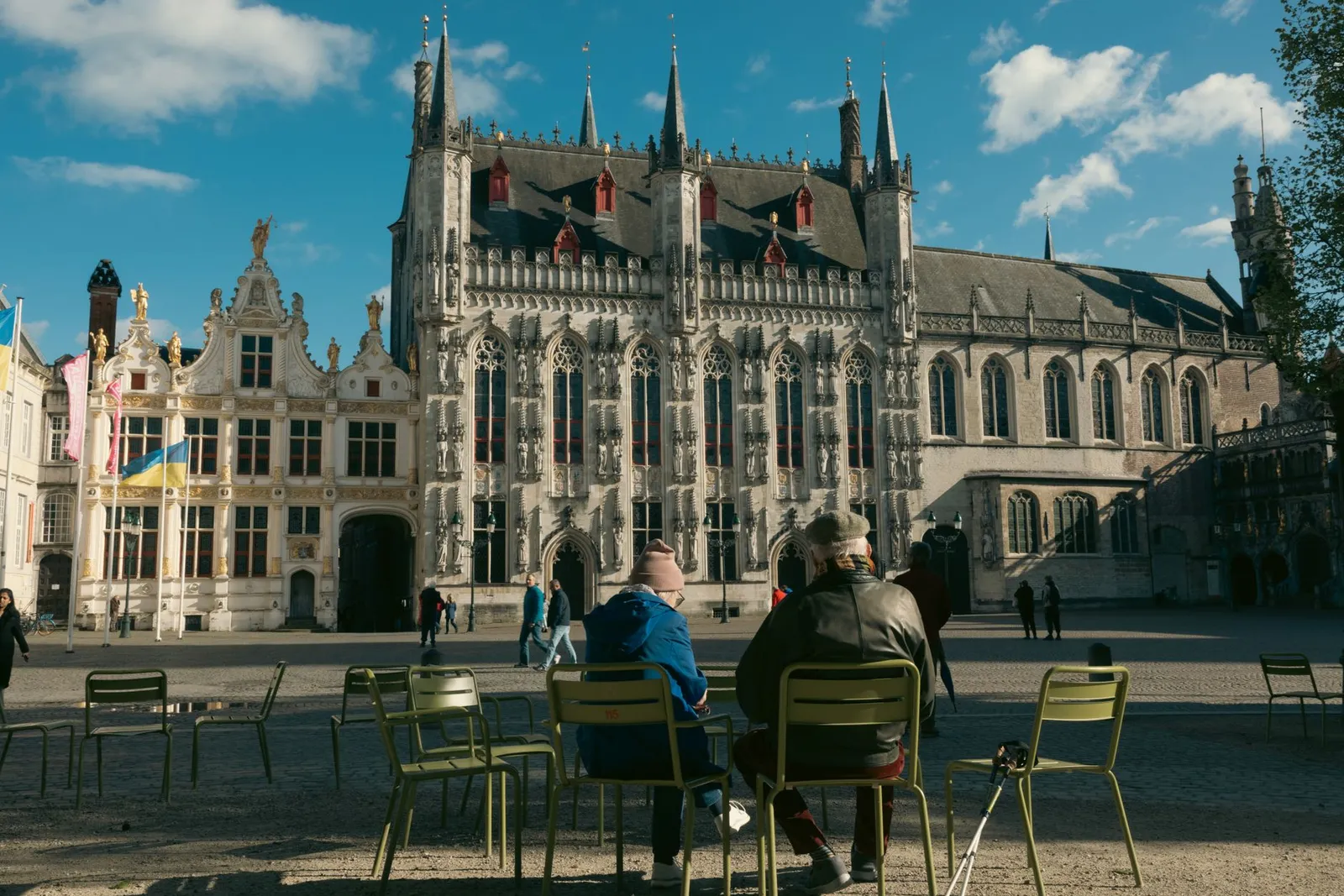 Scenic view of Bruges' De Burg Square with people relaxing on a sunny day.