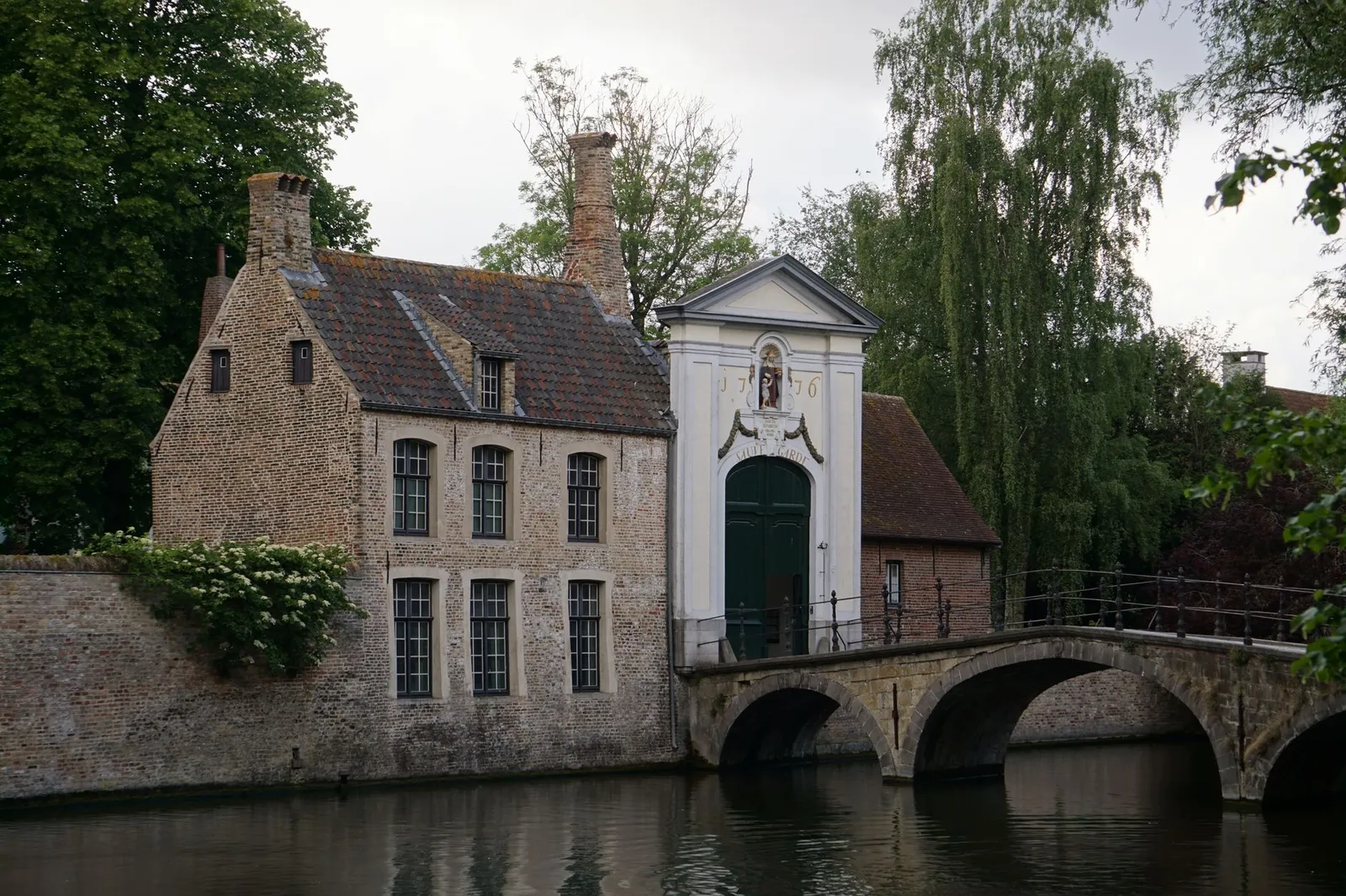 Quaint medieval buildings along the serene canal in Bruges, Belgium, showcasing historic architecture.