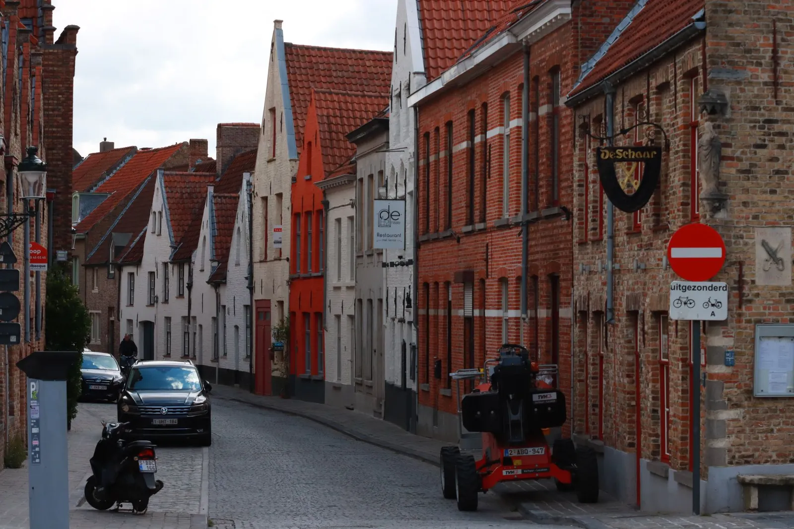 Explore the picturesque, cobbled streets and historic architecture of Bruges, showing buildings, vehicles, and signage.