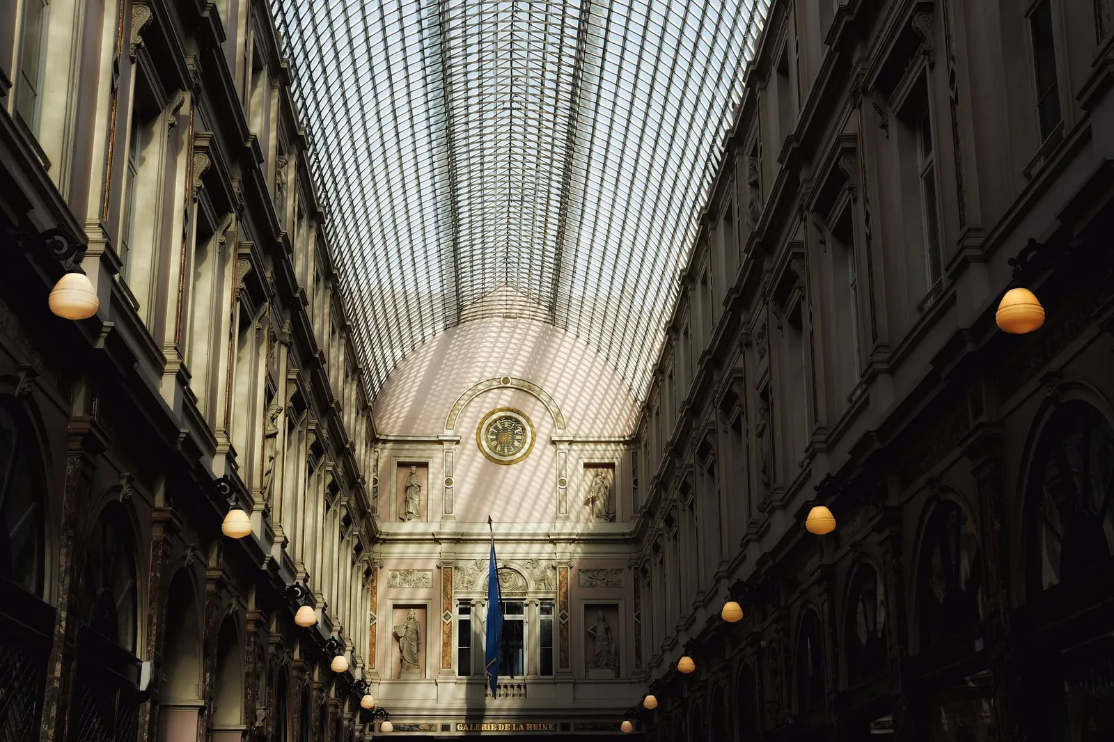 Captivating view of Royal Gallery of Saint Hubert showcasing intricate architecture and sunlight through glass roof.