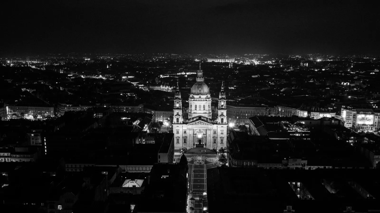 Black and white aerial view of St. Stephen's Basilica illuminated at night in Budapest, Hungary.