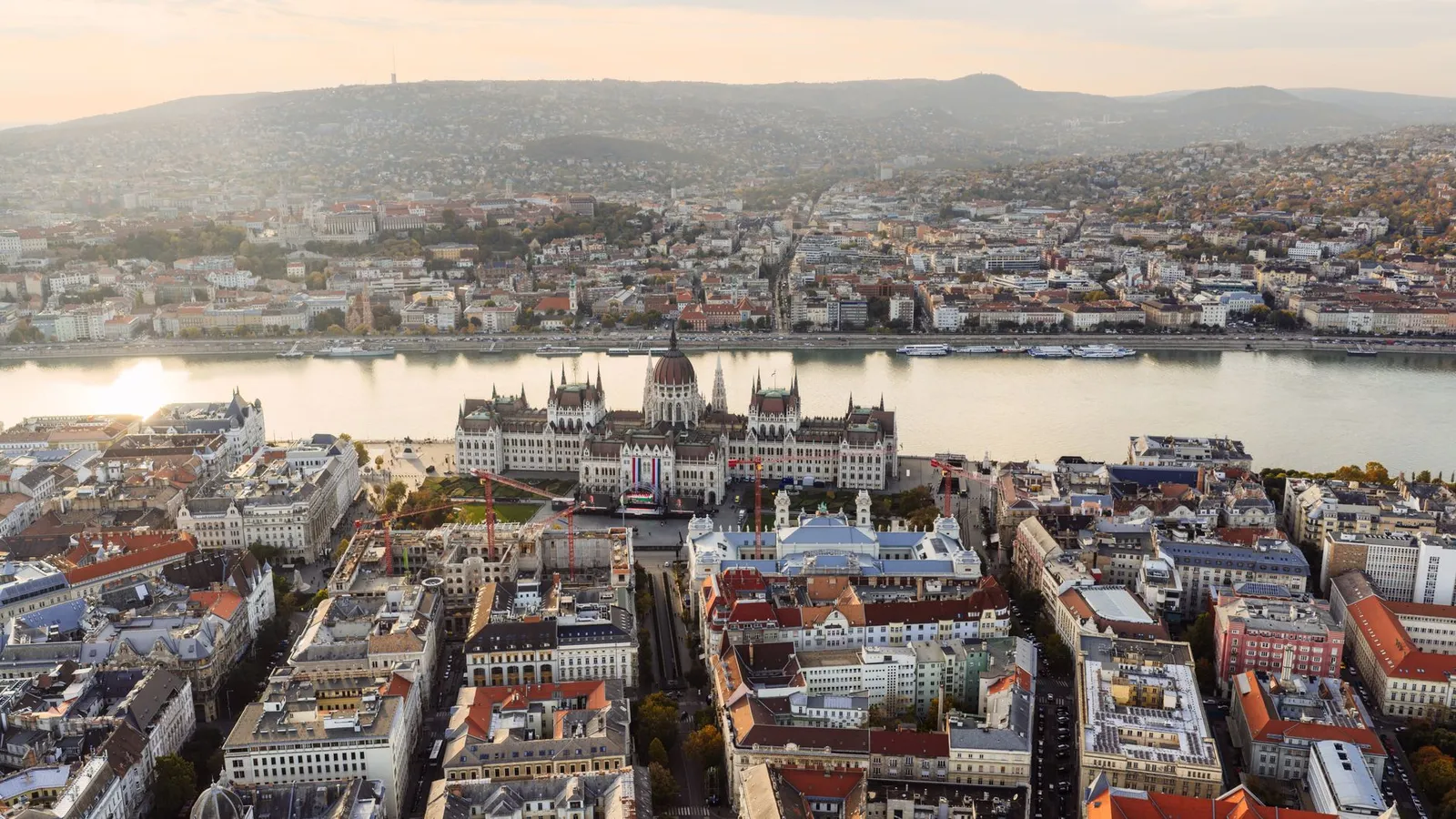 Stunning aerial view of Budapest featuring the iconic Hungarian Parliament Building along the Danube River at sunset.
