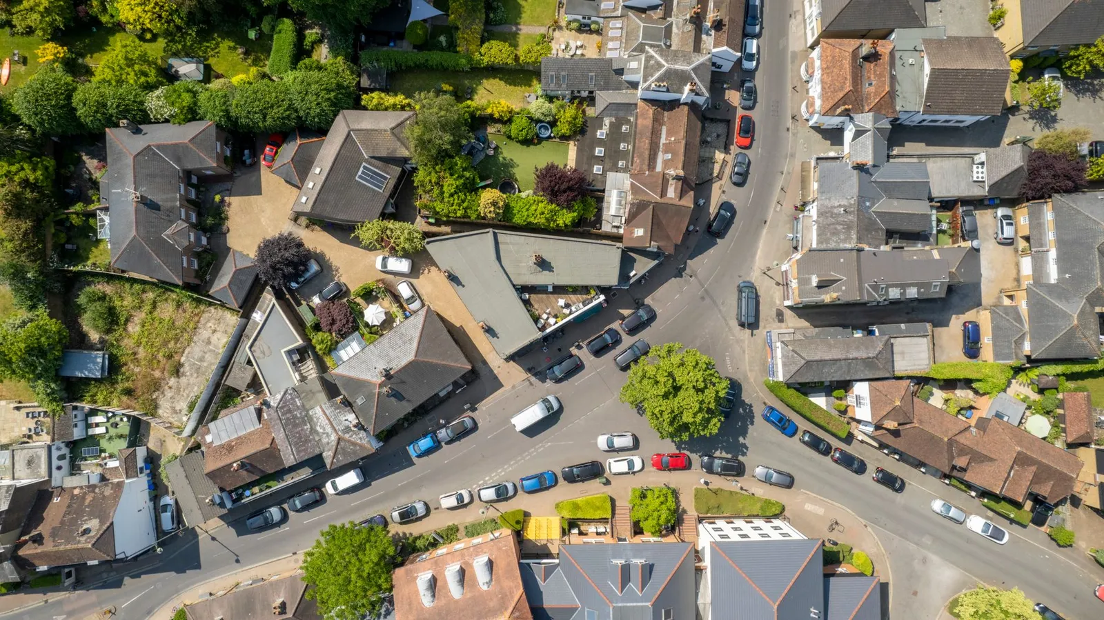 Aerial view of Thames Ditton showcasing roads, cars, and rooftops on a clear day.