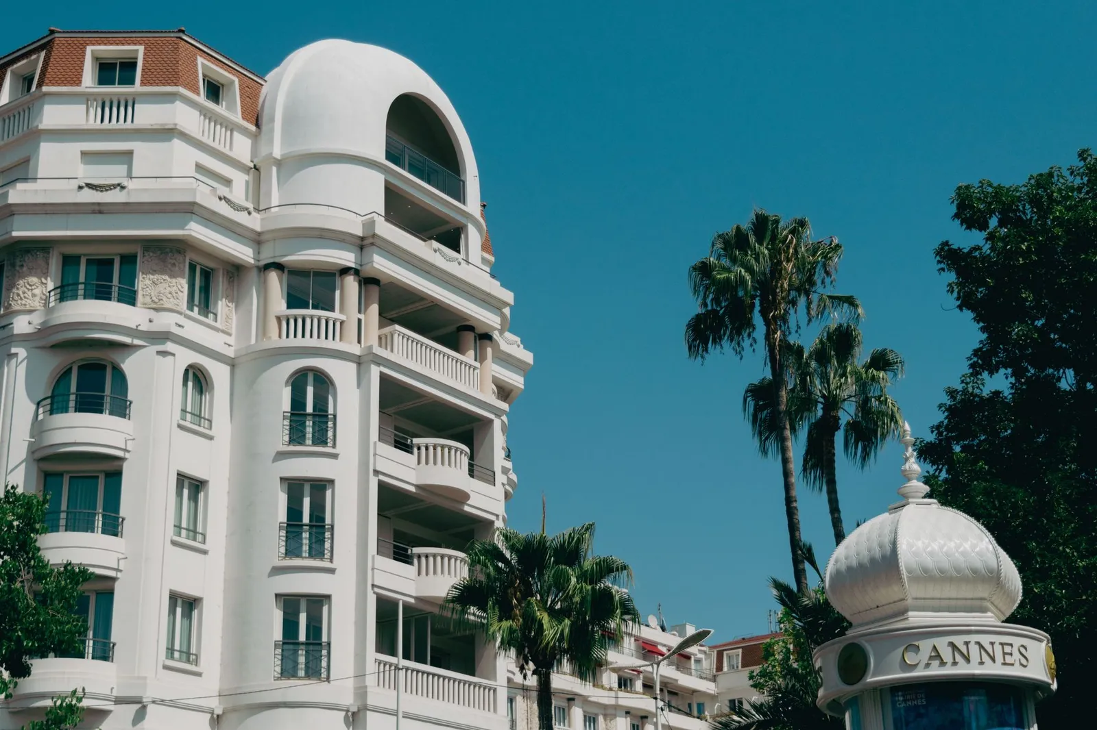 Stunning view of majestic building and palm trees in sunny Cannes, France.