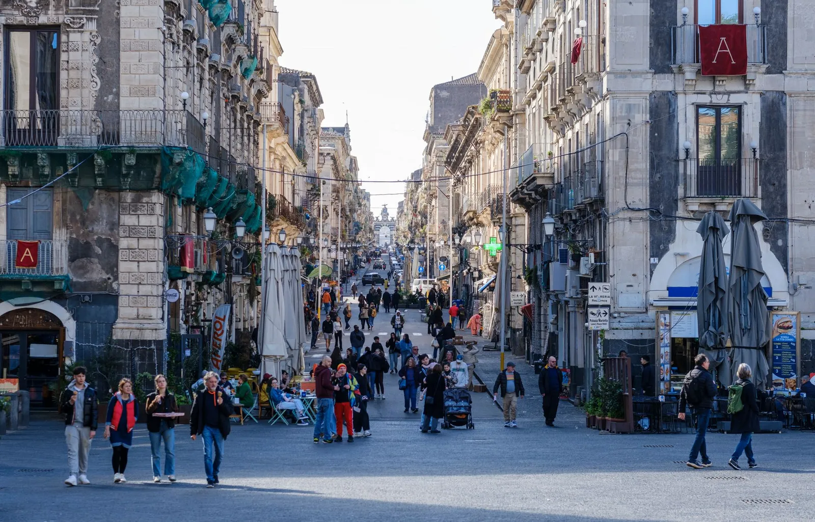 Bustling street scene in Catania, Sicily with historic architecture and pedestrians.