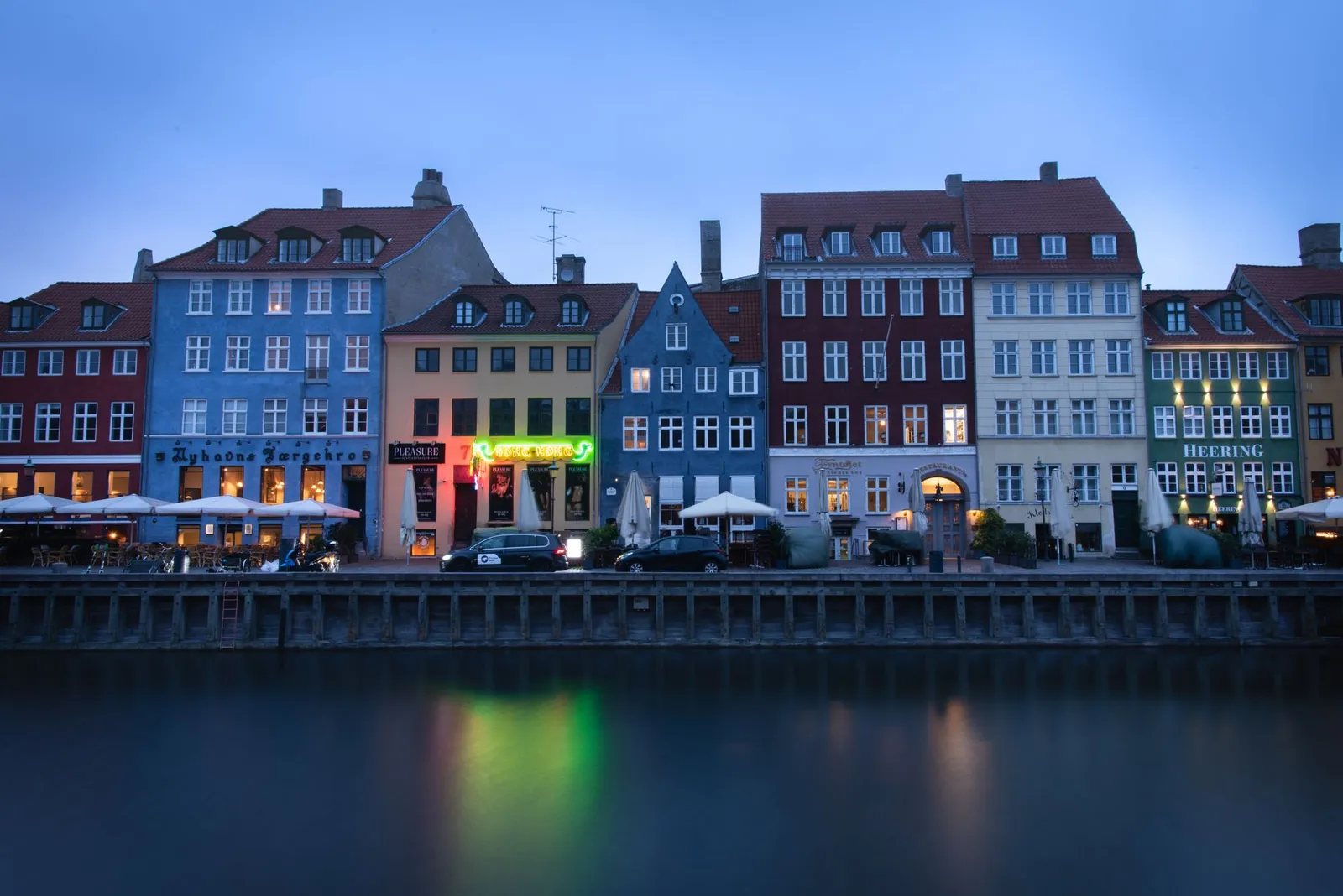 Twilight view of the vibrant Nyhavn waterfront in Copenhagen, Denmark reflecting on water.
