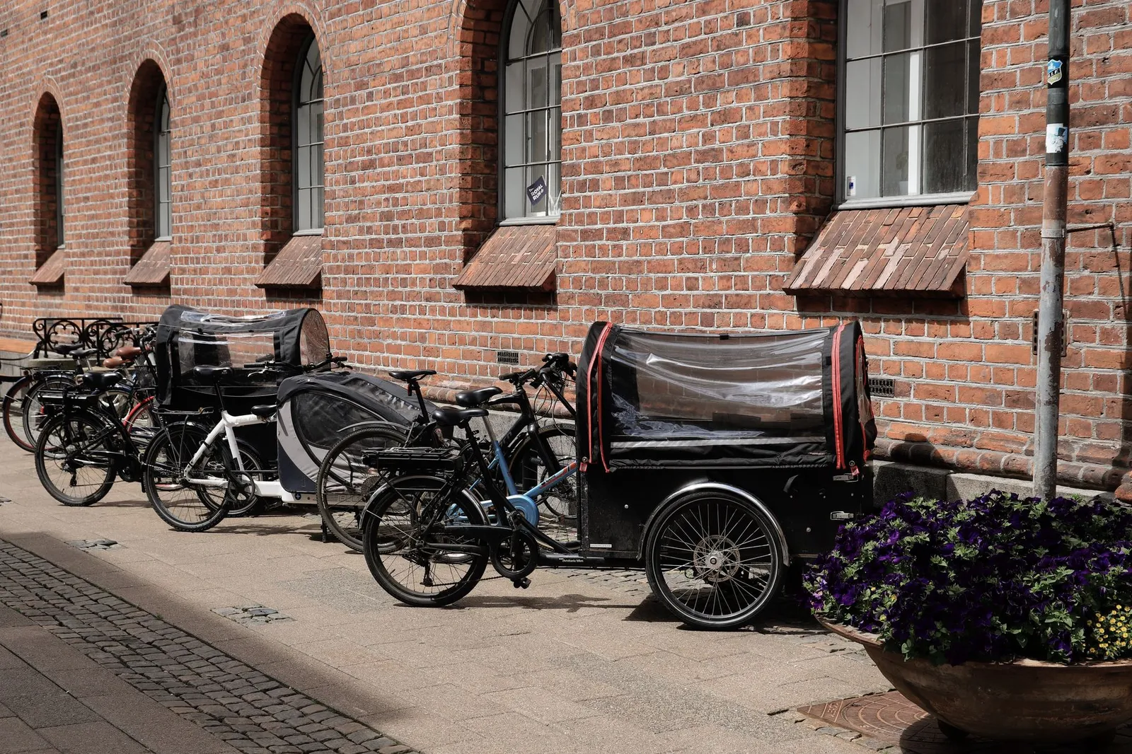 Cargo bikes parked by a red brick wall, showcasing Copenhagen's cycling culture.
