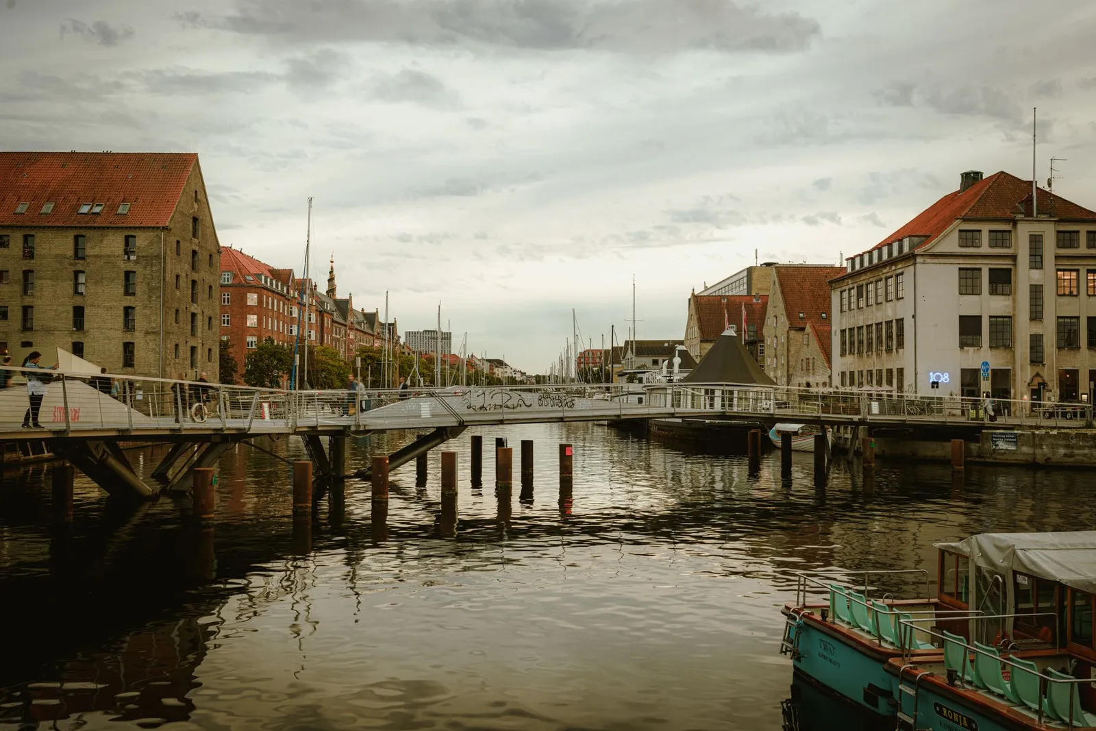 Charming canal scene in Copenhagen with bridges and cityscape at sunset.