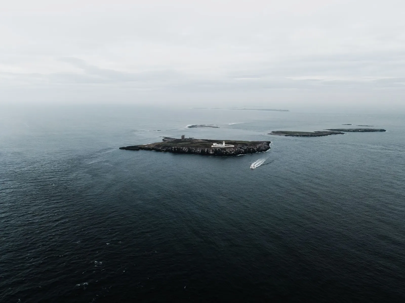 Drone shot capturing the serene Farne Islands and lighthouse in the UK sea.
