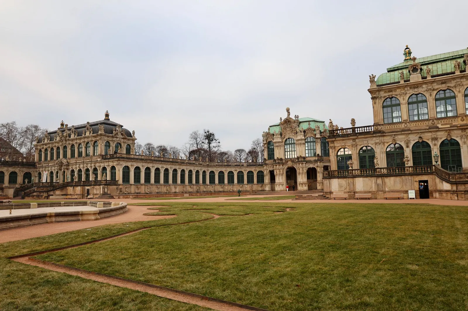A picturesque view of Zwinger Palace in Dresden, showcasing Baroque architecture and green lawns.