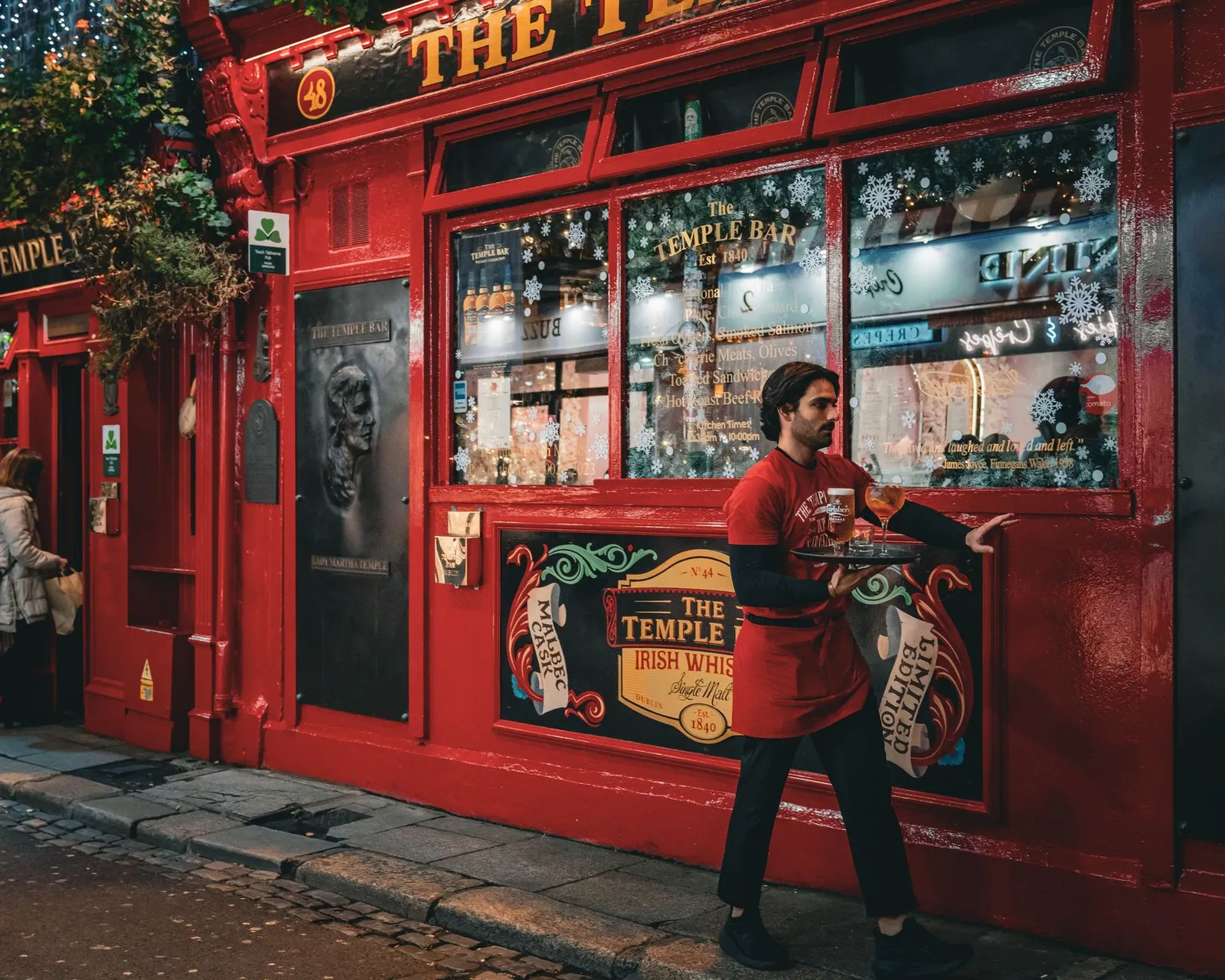 Waiter carrying a tray outside the famous Temple Bar in Dublin, Ireland.