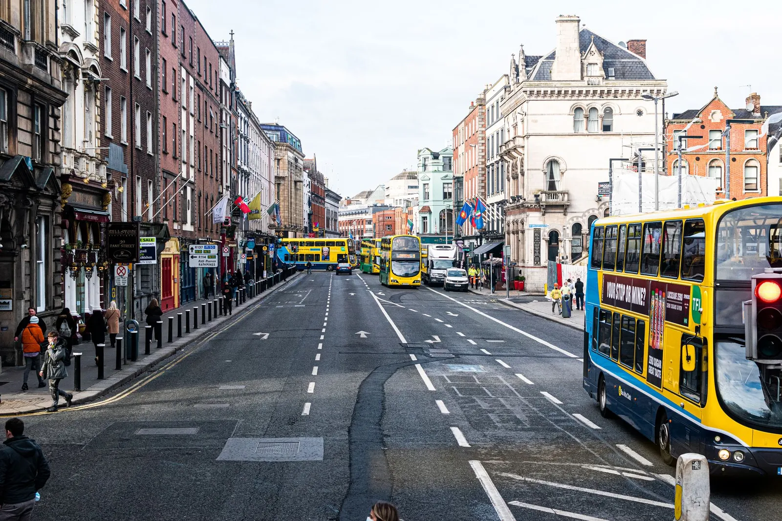 Vibrant city street scene in Dublin with buses and pedestrians on a busy day.