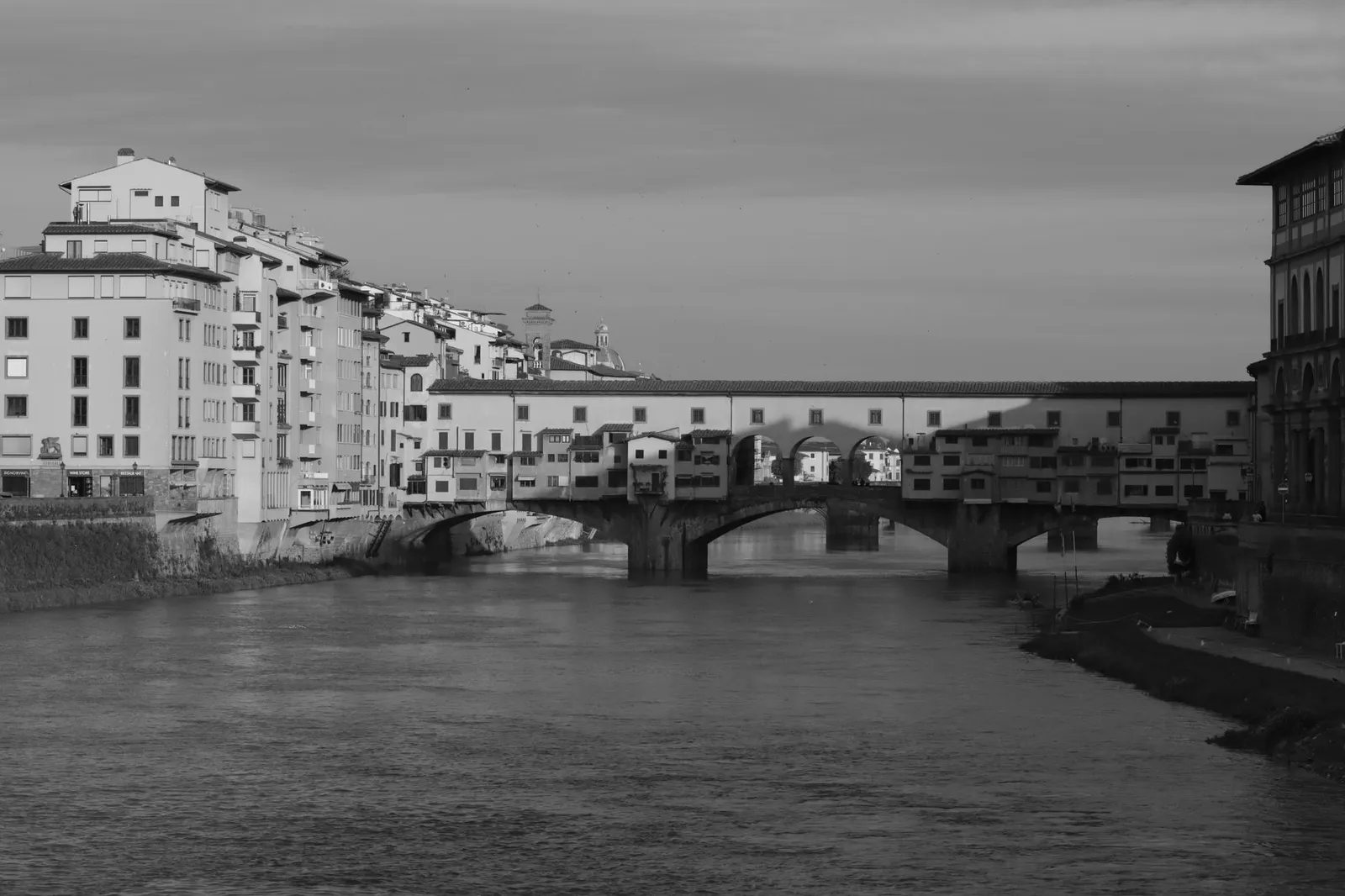 Monochrome image of the historic Ponte Vecchio bridge over the Arno River in Florence, Italy.