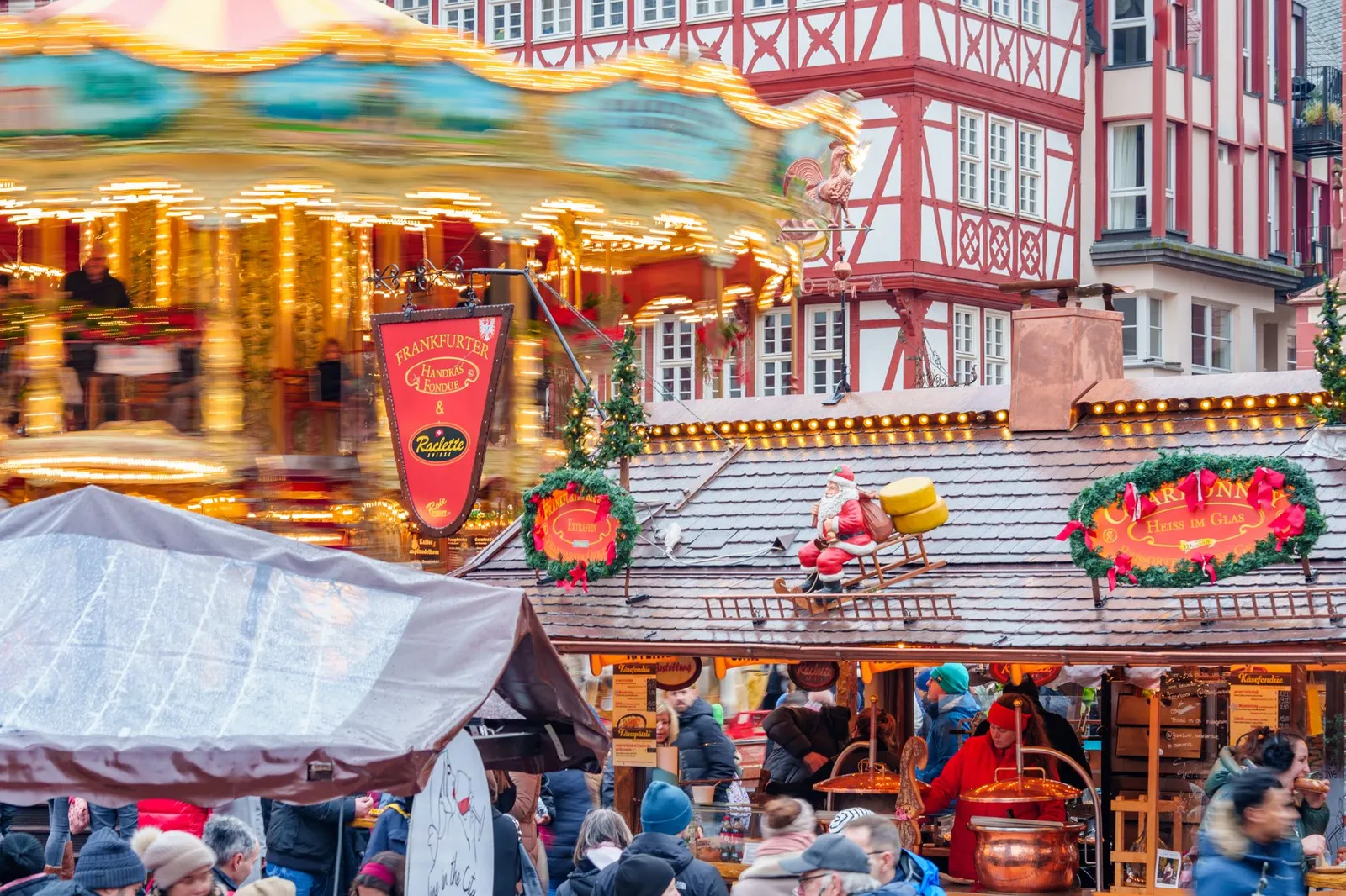 A vibrant scene at Frankfurt's Christmas market with people, carousel, and festive decorations.