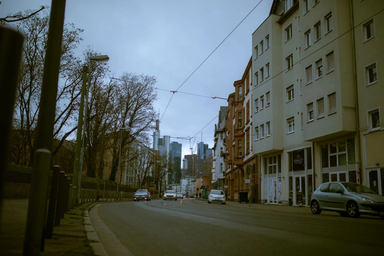 Street view of Frankfurt showcasing apartment buildings and cars on a cloudy day.