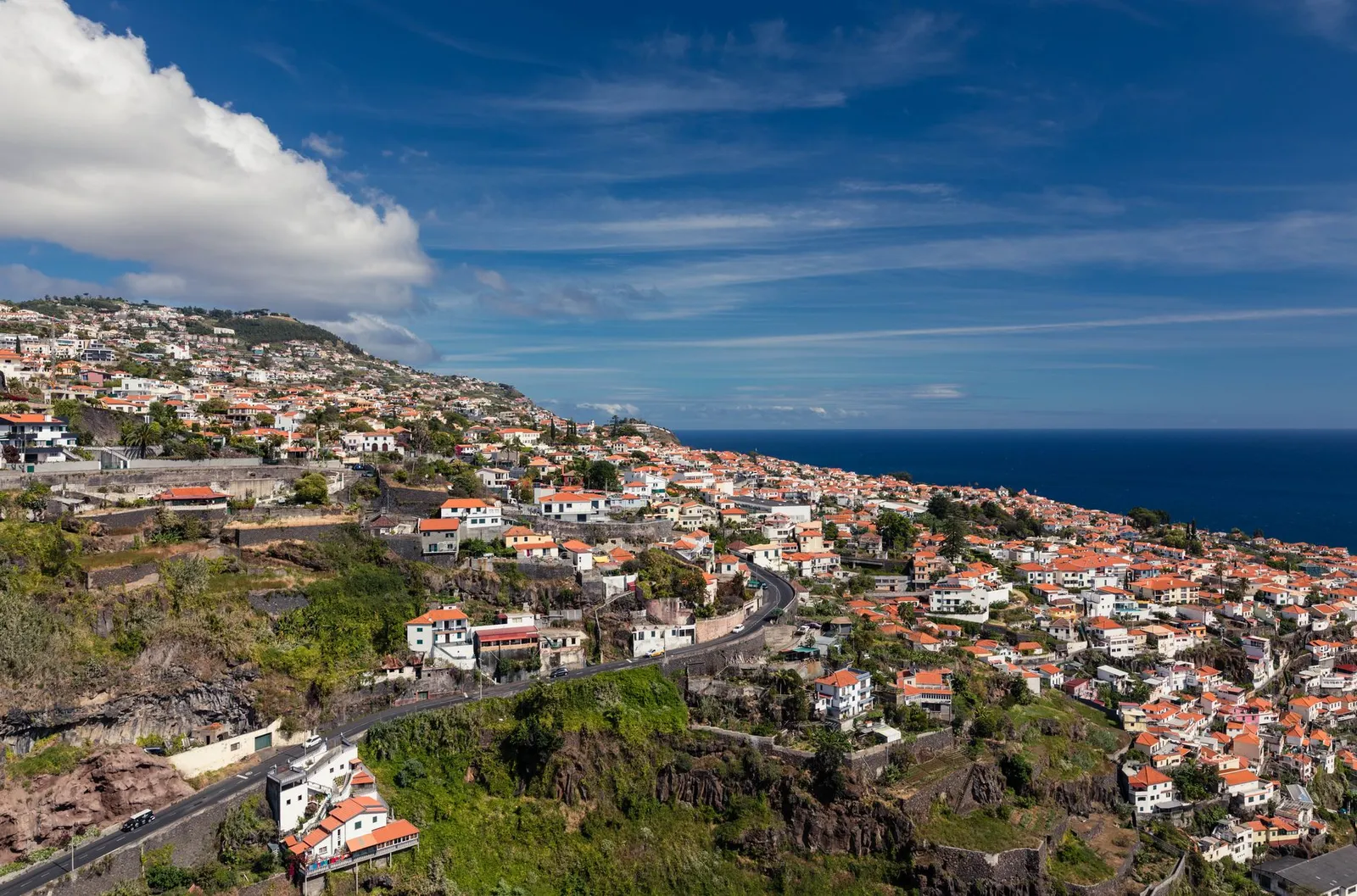 A scenic aerial view of Funchal, Madeira with charming red-roofed houses under a bright blue sky.