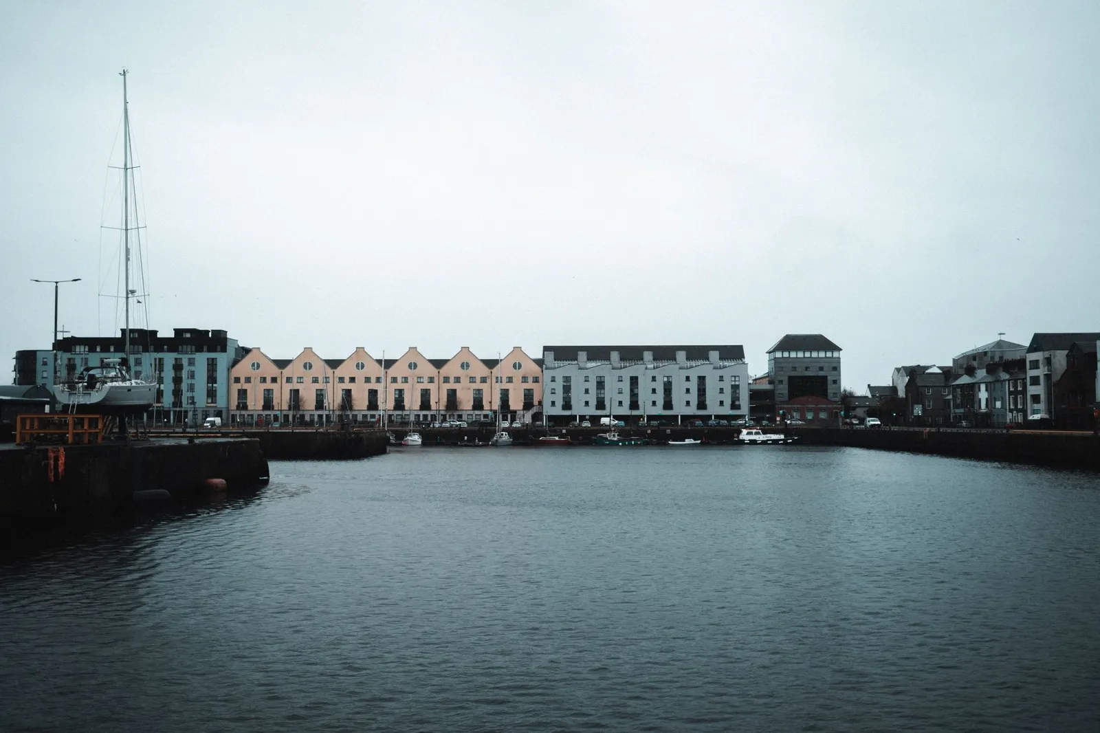 Scenic view of Galway Harbor with colorful townhouses and boats, showcasing urban waterfront architecture.