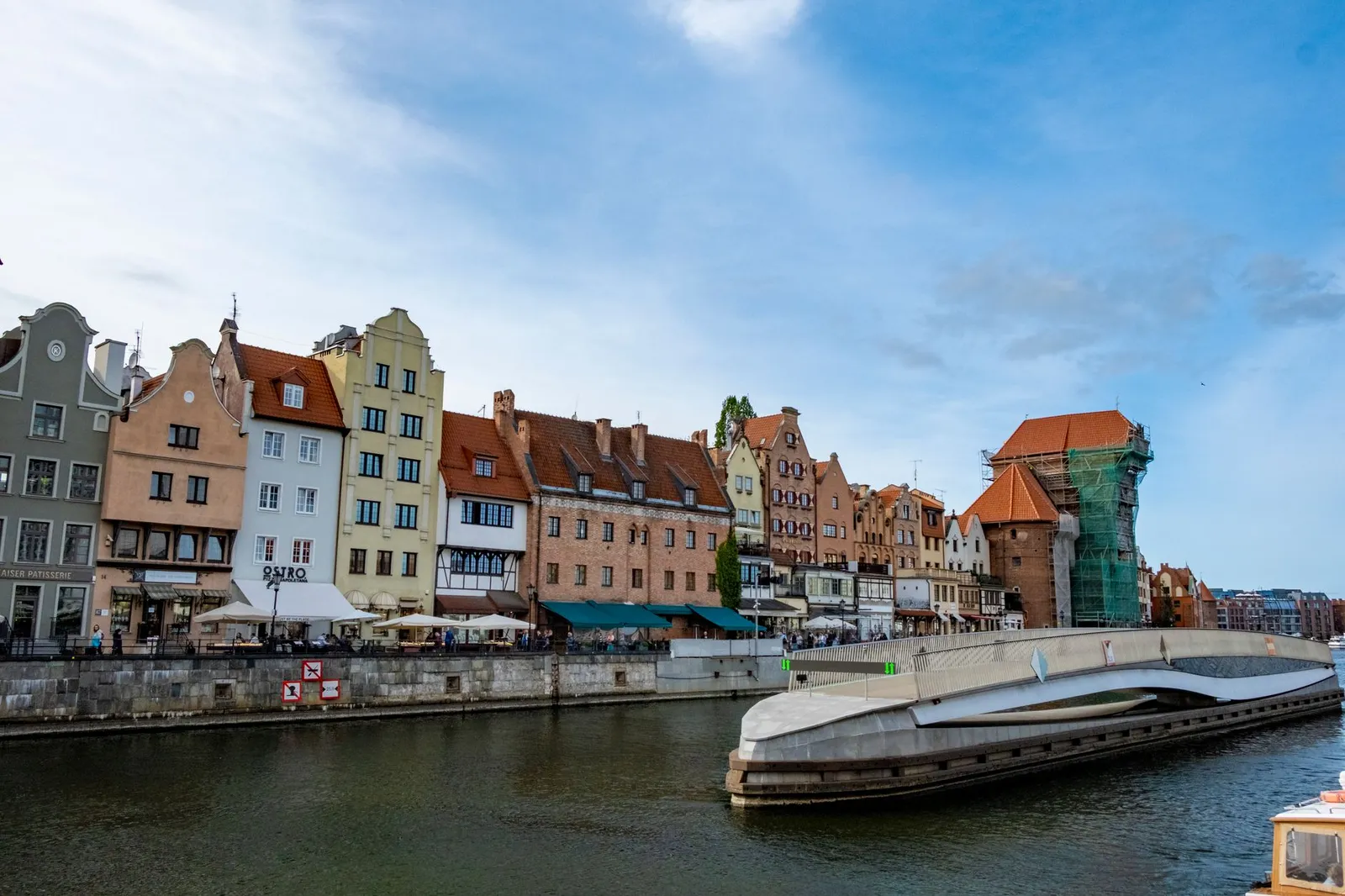 Charming riverside architecture in Gdańsk, showcasing historical buildings and a modern bridge.