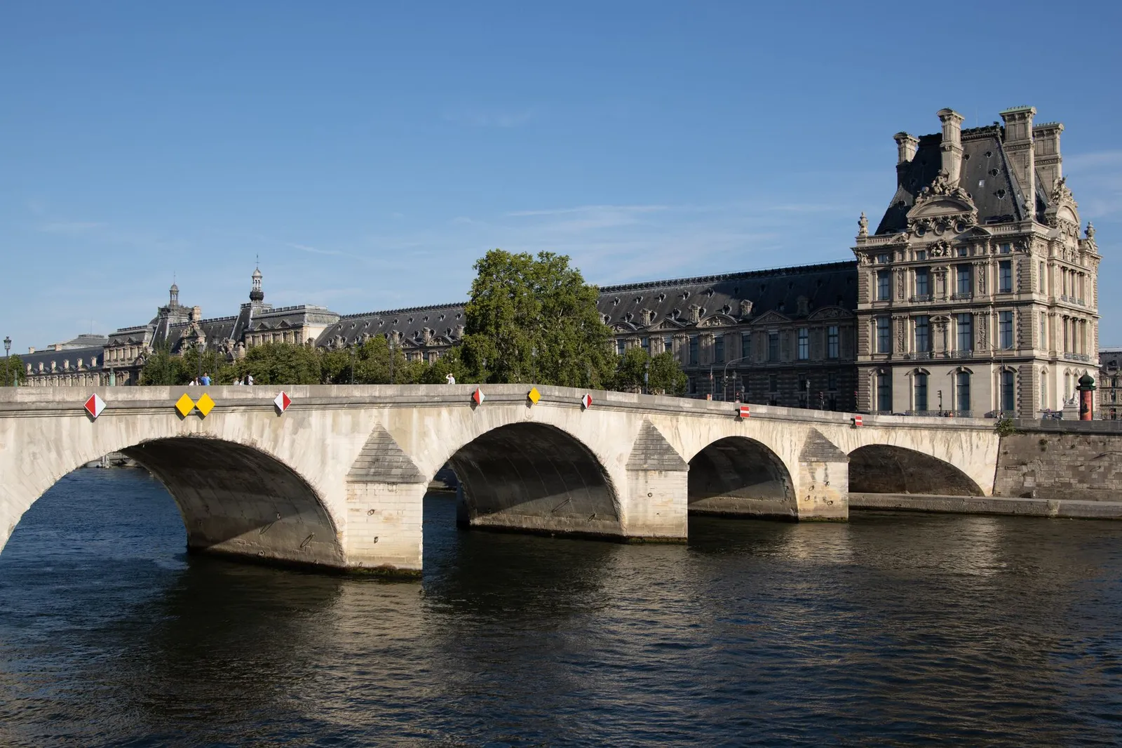 A scenic view of a historic bridge crossing the Seine River with classic Parisian architecture in the background.