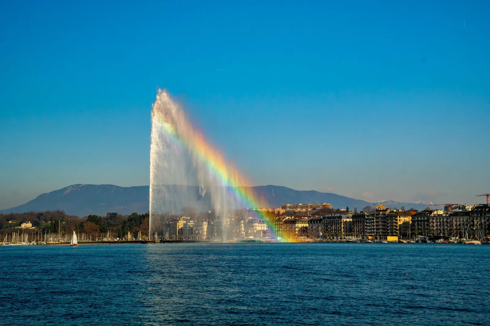 Stunning view of Jet d'Eau fountain with a rainbow over Lake Geneva in Switzerland.