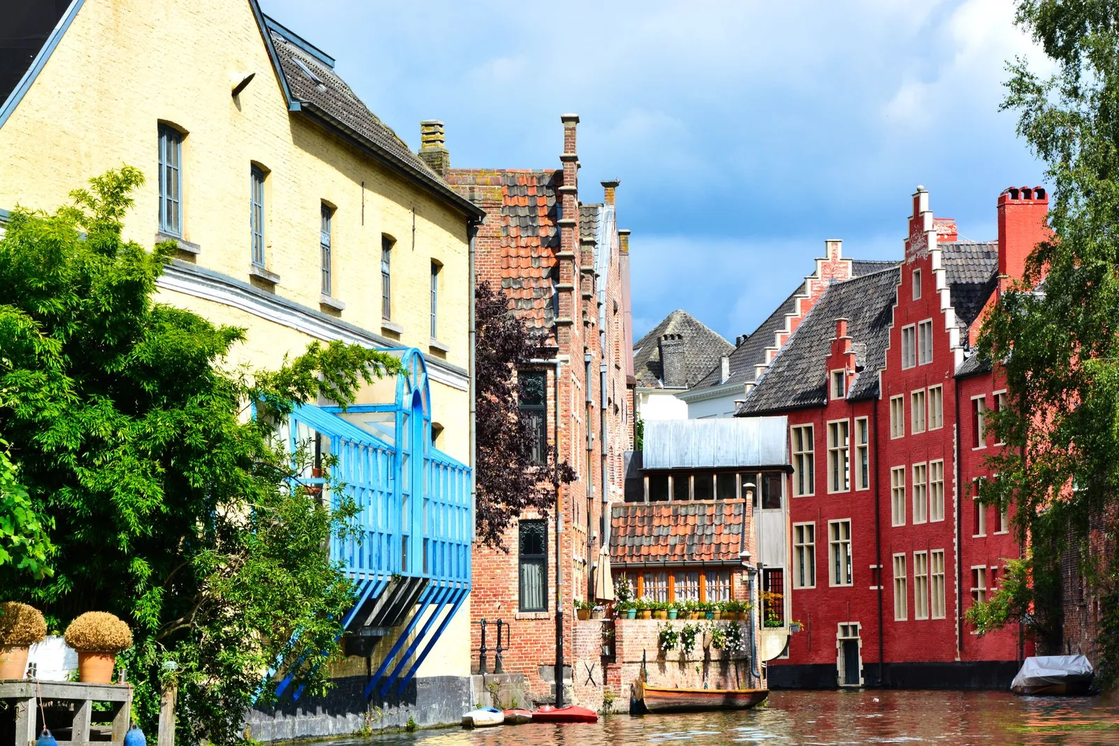 Charming canal houses with colorful facades in Ghent, Flanders, reflecting vibrant architecture.