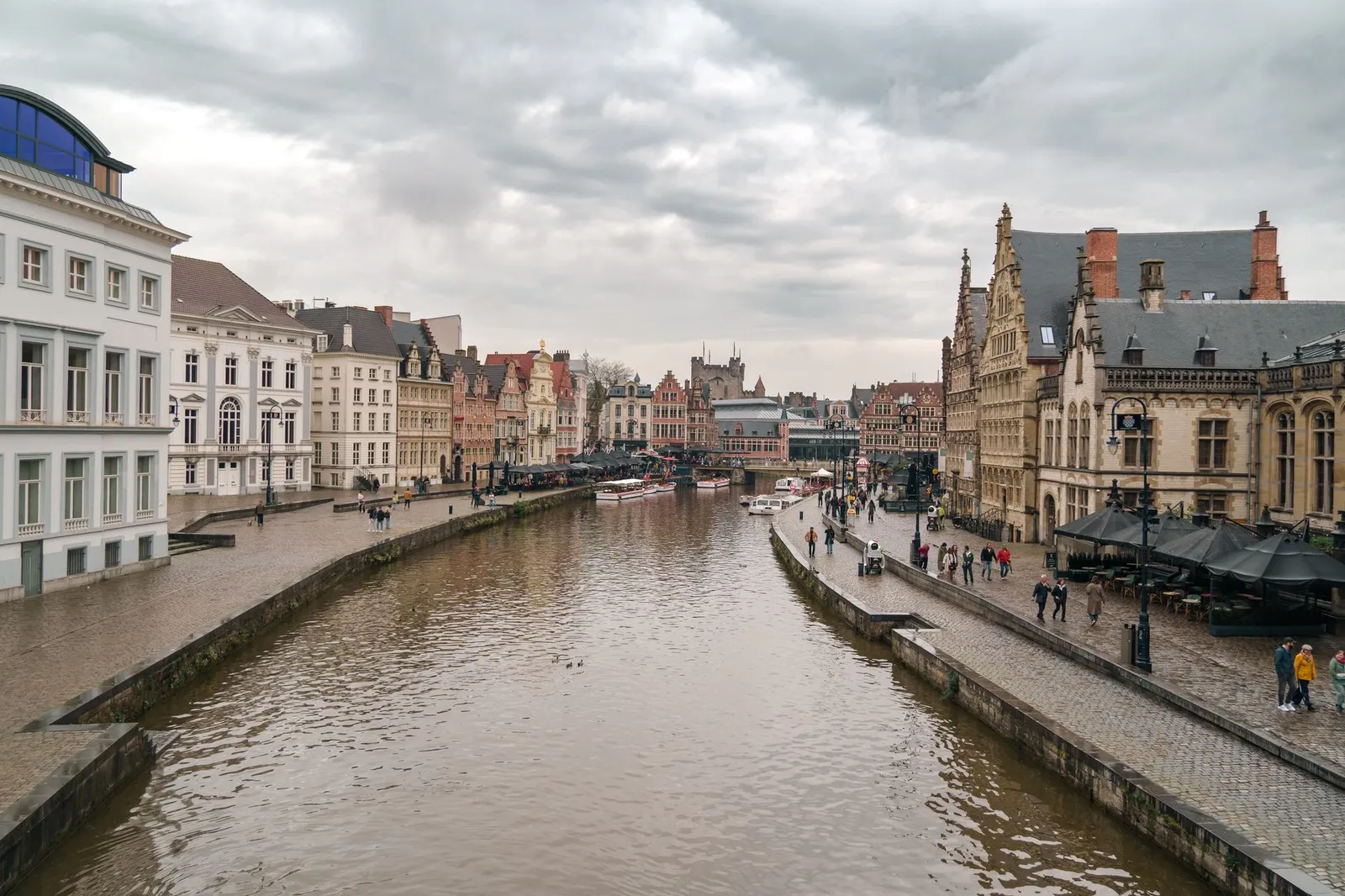 Charming canal scene in Ghent, Belgium with historical architecture on a cloudy day.