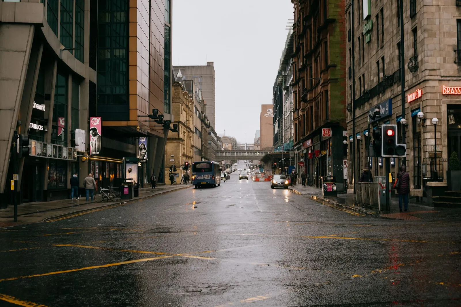 A rainy day in Glasgow's city center with traffic and pedestrians on wet streets.