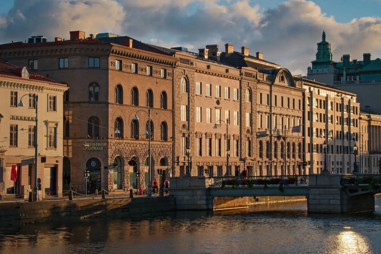 Sunlit view of historical architecture and bridge over water in Gothenburg, Sweden.