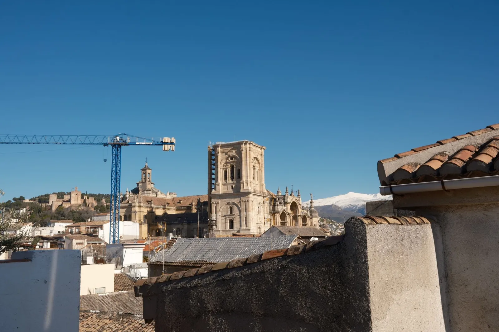 A view of Granada Cathedral with the cityscape and Sierra Nevada mountains in the background.