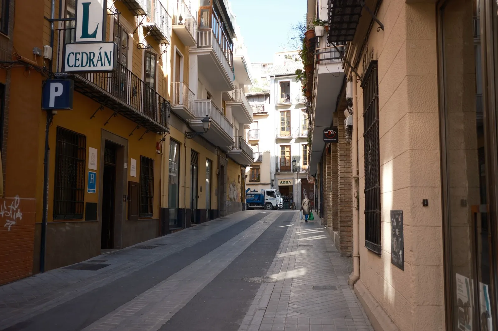 Explore a quiet narrow street in Granada, flanked by picturesque buildings and a calm atmosphere.