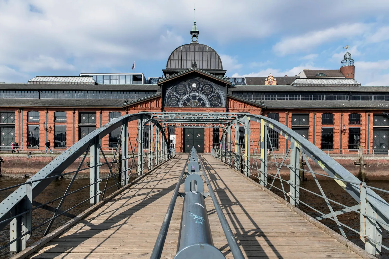 View of the historic Fish Auction Hall in Hamburg, Germany, with its iconic footbridge under a clear sky.