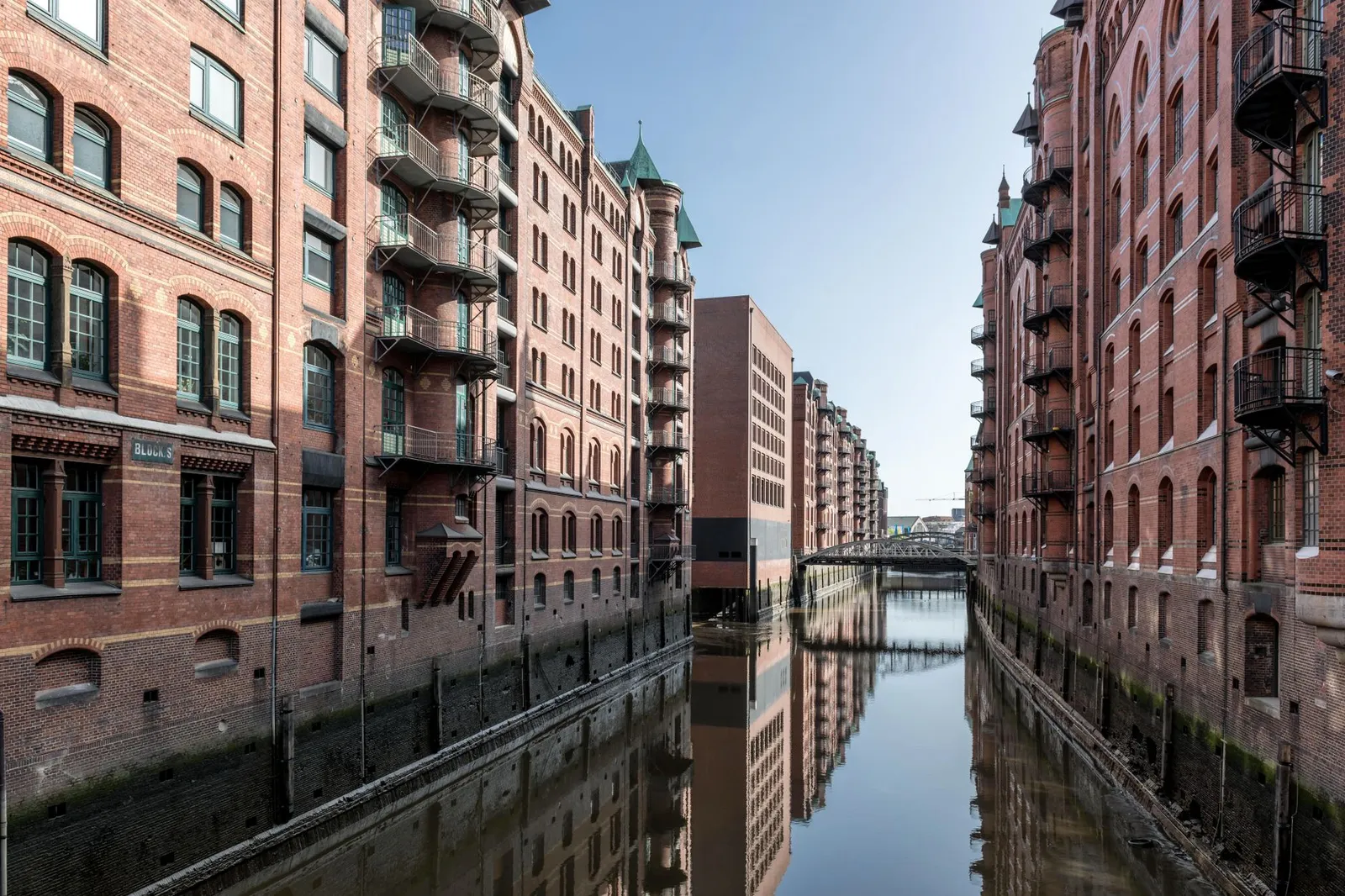 View of historic brick warehouses reflecting in a canal in Hamburg's Speicherstadt.