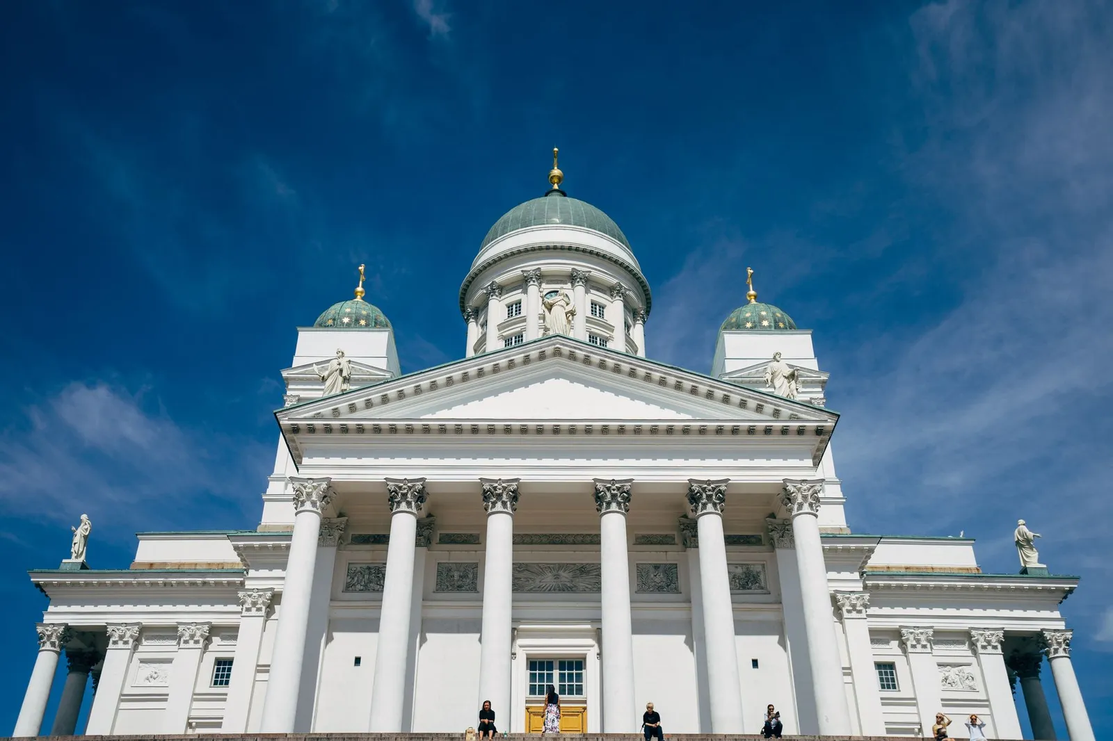 Front view of Helsinki Cathedral against a bright blue sky, highlighting neoclassical architecture.