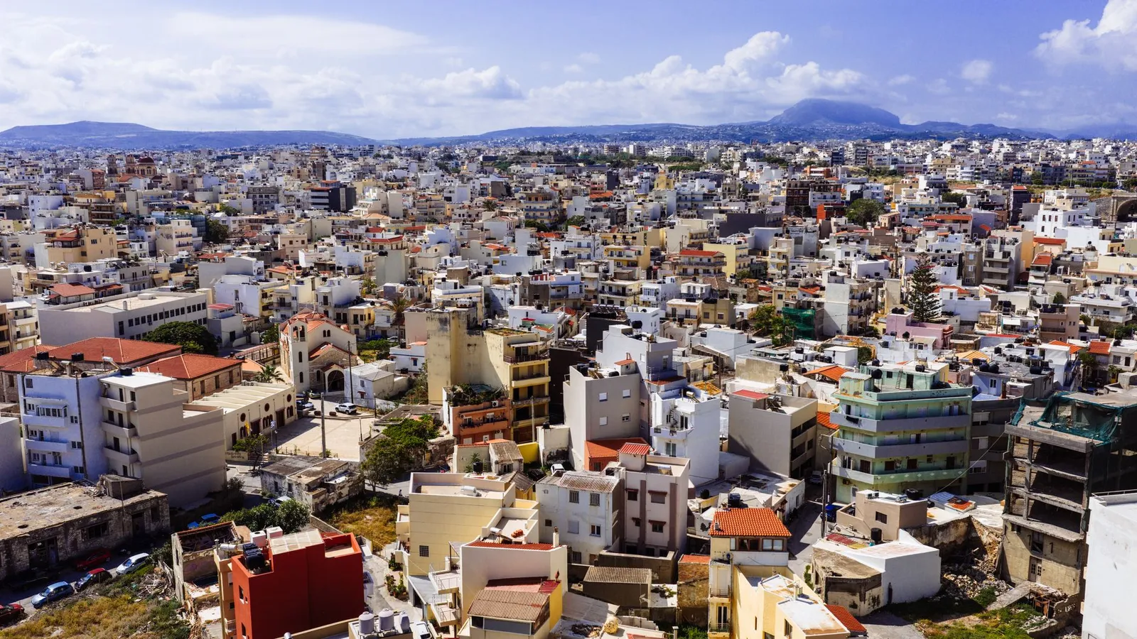 Discover the vibrant cityscape of Heraklion, Crete, captured from above with a stunning view of buildings and mountains.